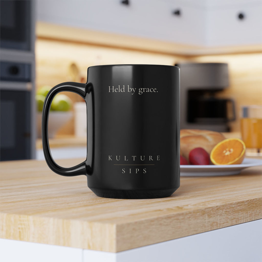 Carried Grace Collection black ceramic mug on kitchen counter showing “Held by grace” message